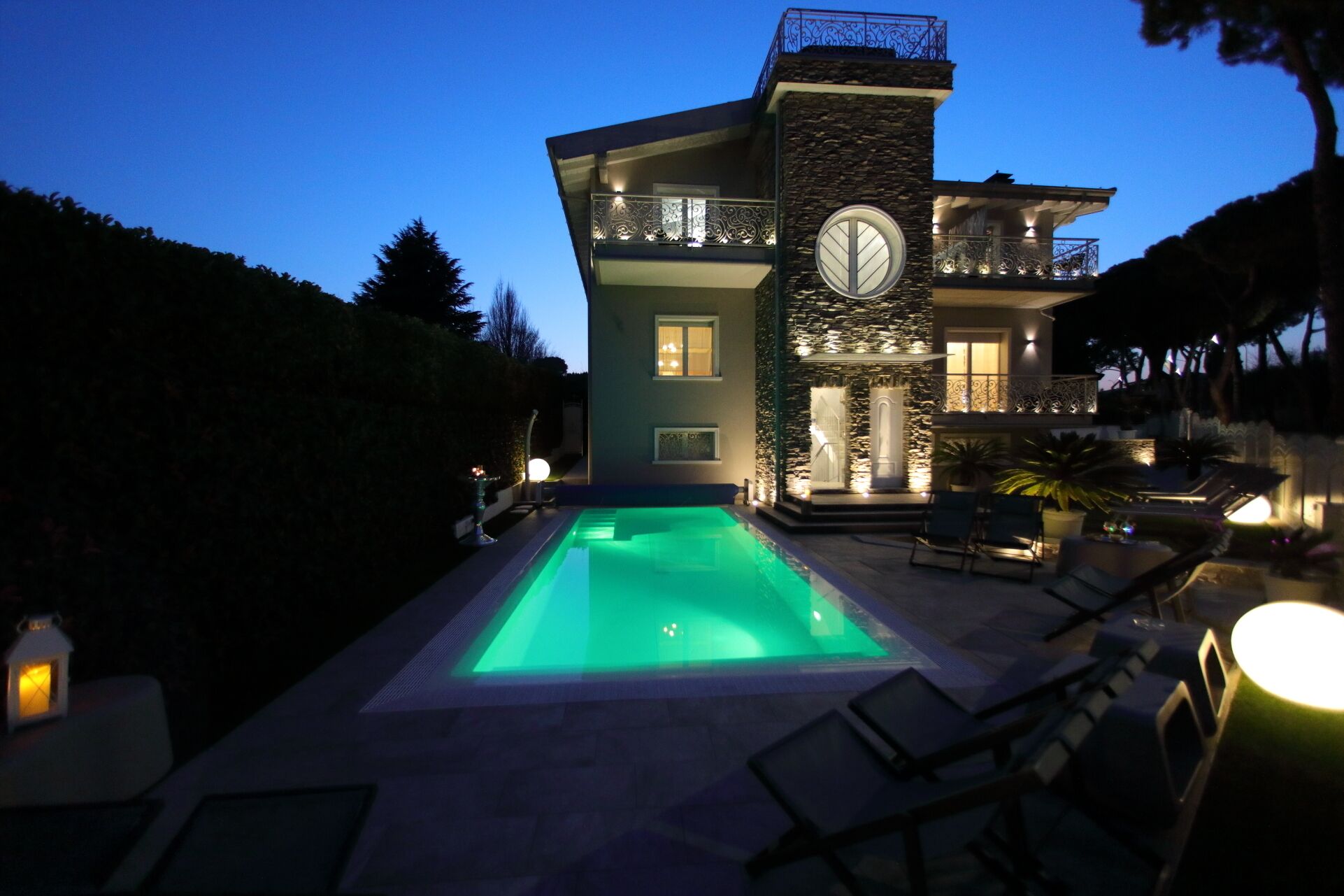 Una casa grande con piscina, mobiliario exterior y fachada de piedra.
