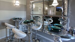 A room with mirrored walls, chrome bar stools, and a mirrored bar counter.