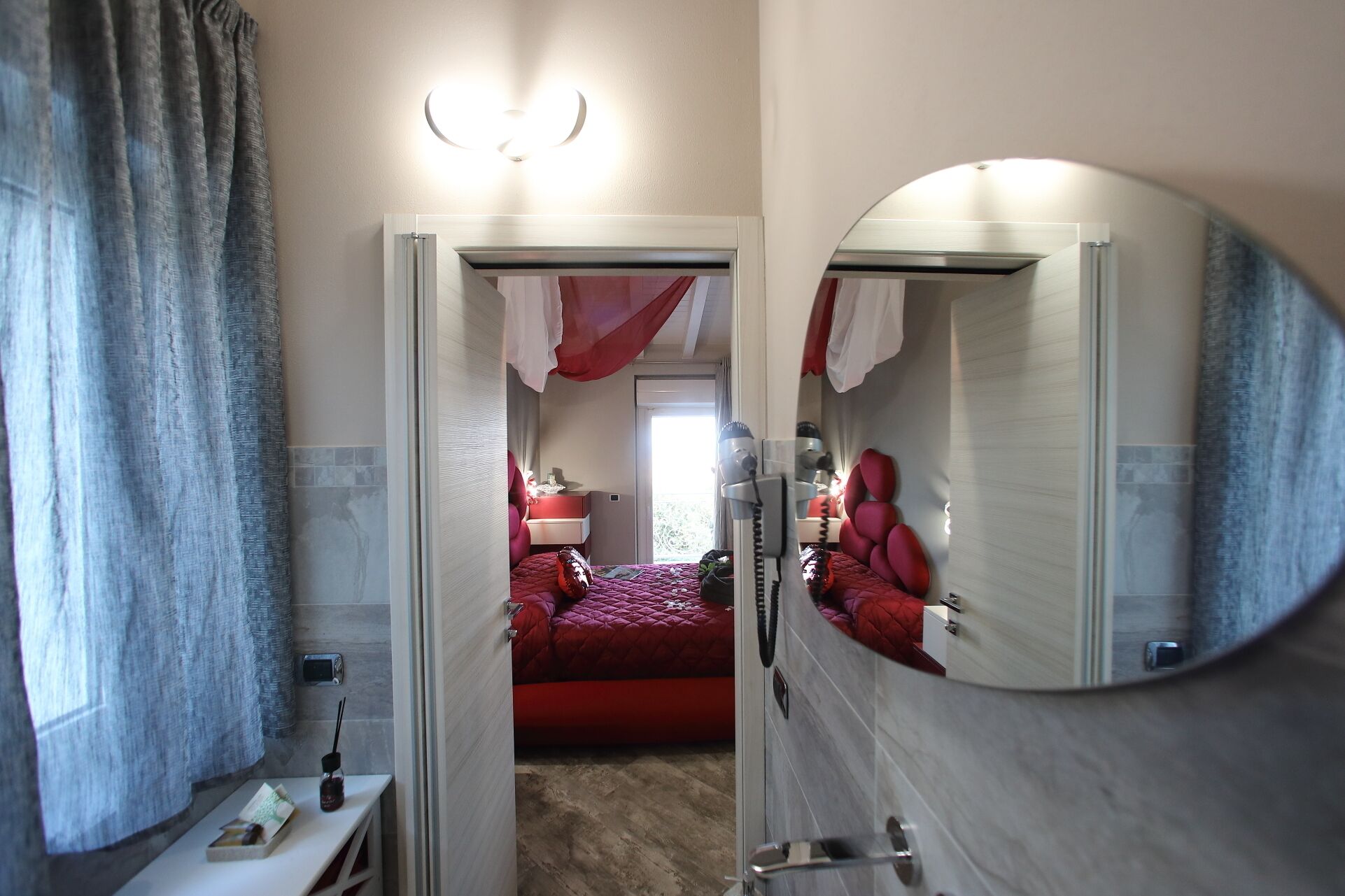 Une chambre d’hôtel avec un lit, une table de chevet, un miroir et une fenêtre.
