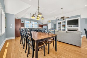A spacious living area with a dining table, chairs, a sofa, and a television.