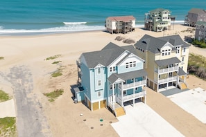 A beachfront property with multiple buildings, including a large house with a balcony and a smaller structure. - Cape Point, charming 7-Bedroom Oceanfront + Pets Stay Free! (Buxton)