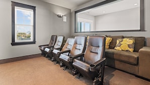 Una habitación con cuatro sillones reclinables, un sofá y un espejo grande.