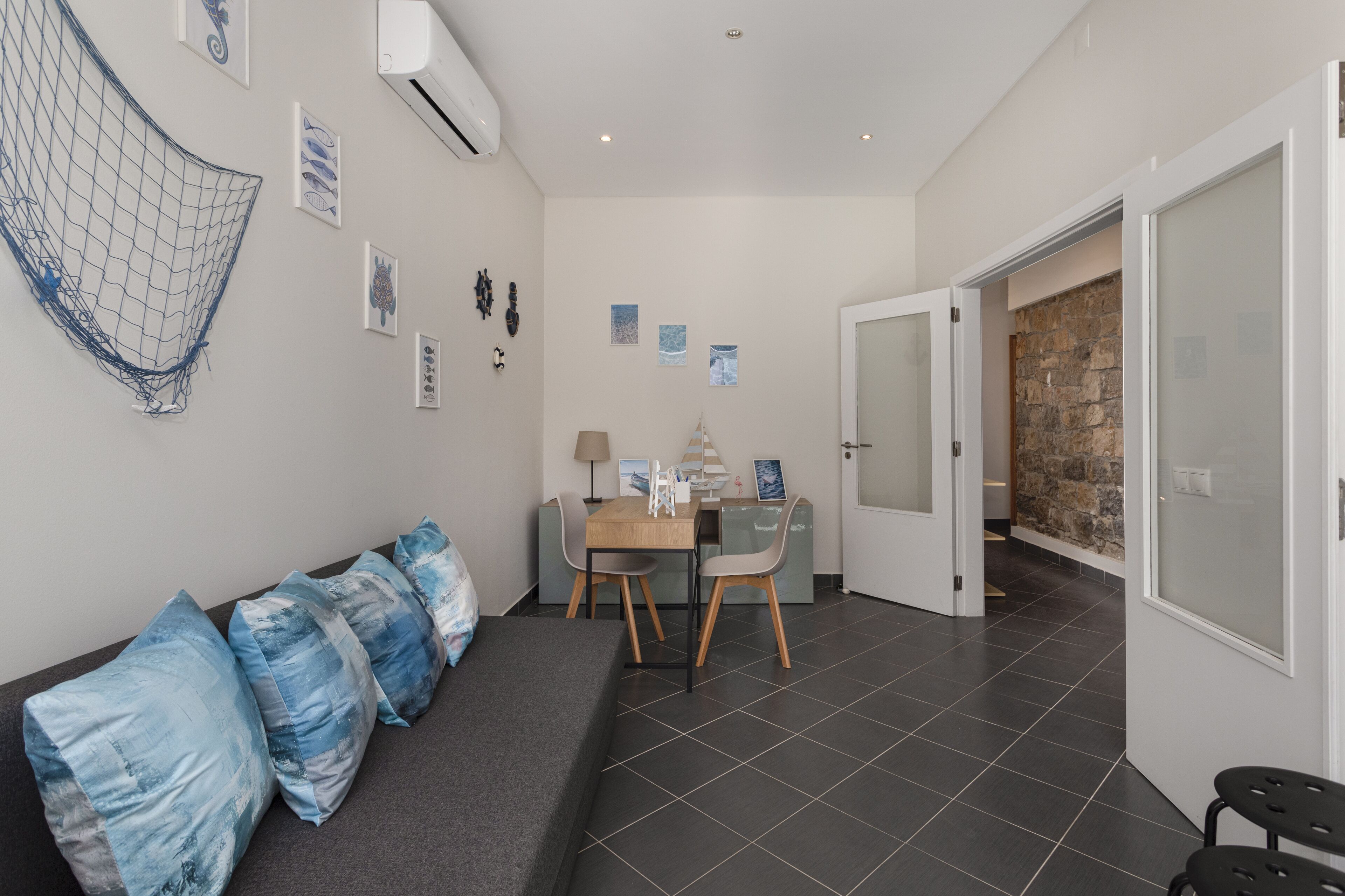 A modern room with a sofa, a dining table with chairs, and a stone wall.