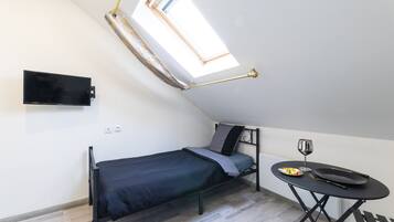 Une petite chambre moderne, équipée d’un lit, d’un bureau et d’une table à manger.