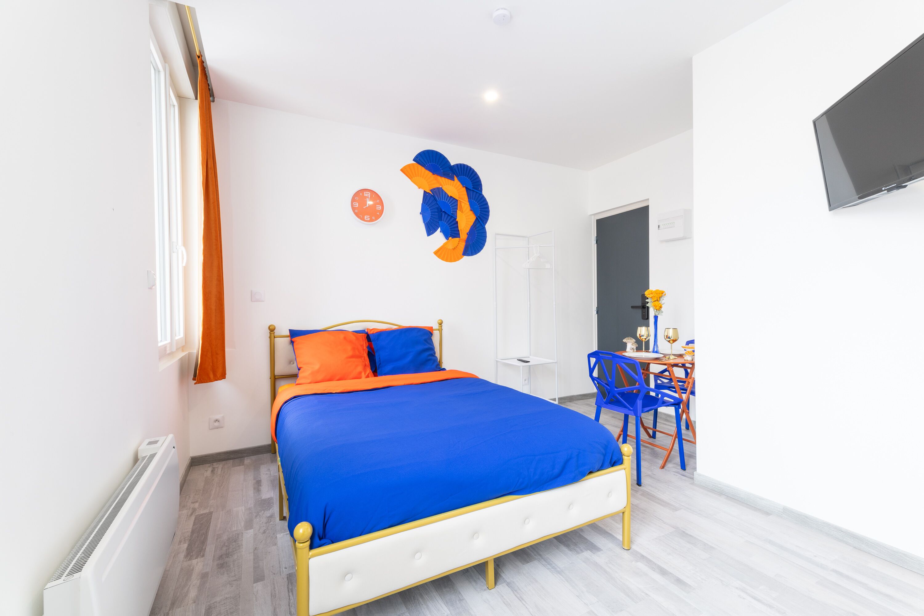 A bedroom with a bed, a TV, a chair, and a table.
