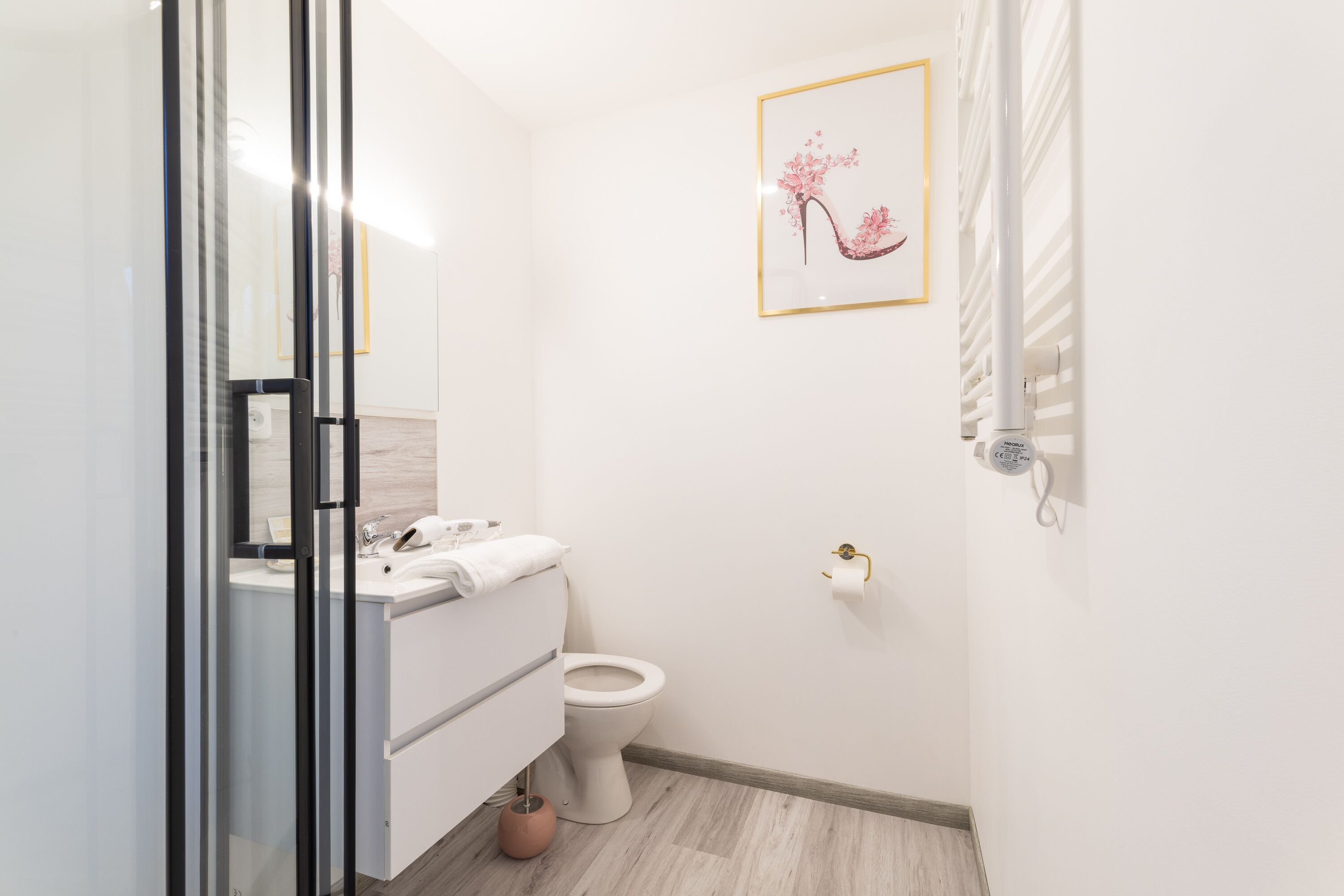 A modern bathroom with a glass shower enclosure, a white toilet, and a sink with a towel.