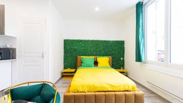Une chambre à coucher avec un lit, un mur vert, une fenêtre et une porte.