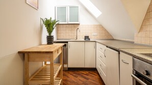 A compact kitchen with a wooden table, a built-in dishwasher, and a small window above the sink. - RentPlanet - Apartament Odrzańska (Wroclaw)