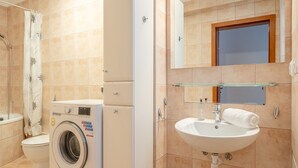 A bathroom with a washing machine, toilet, sink, and a mirror above the sink. - RentPlanet - Apartament Odrzańska (Wroclaw)