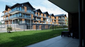 A modern multi-story residential building with balconies, a paved driveway, and a well-maintained lawn. - Apartamenty Sun & Snow Żeglarska (gmina Lodygowice)