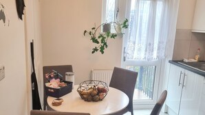 Un coin repas avec une table ronde, deux chaises, une plante et une fenêtre avec des rideaux.