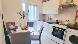 Une cuisine compacte avec un coin repas, comprenant un lave-vaisselle, un four et un lave-linge.
