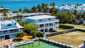 A resort with multiple-story buildings, a swimming pool, and a view of the ocean.