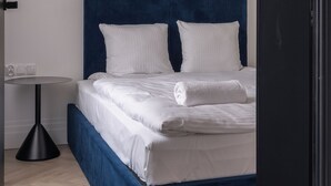 Une chambre à coucher moderne avec un grand lit, une table de chevet et une lampe sur pied.