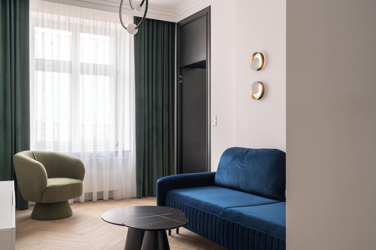 A modern living room with a blue sofa, a green armchair, and a round black coffee table.