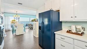 A modern kitchen with white cabinets, a blue refrigerator, and a coffee maker on the counter. - Ground level bay-front home on deep waterfront!  (Dauphin Island)