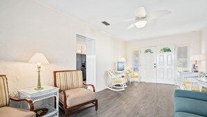 A spacious living room with a wooden floor, a ceiling fan, and a dining area with a table and chairs. - Ground level bay-front home on deep waterfront!  (Dauphin Island)