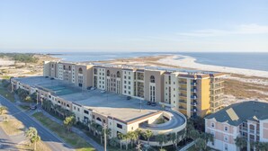 Een meerlaags hotel met een zwembad op het dak, gelegen nabij een strand met zand en uitzicht op zee.