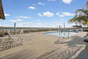 Zona de piscina con sillones de descanso, piscina y vista al océano.