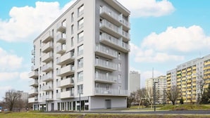 Kerrostalo, jossa on useita kerroksia, parvekkeet, tasakatto ja moderni arkkitehtoninen tyyli.