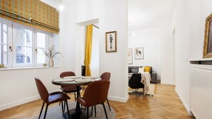 Een eethoek met een ronde tafel, vier stoelen en een raam met gordijnen.