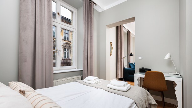 Een hotelkamer met een bed, bureau, stoel en een raam met gordijnen.