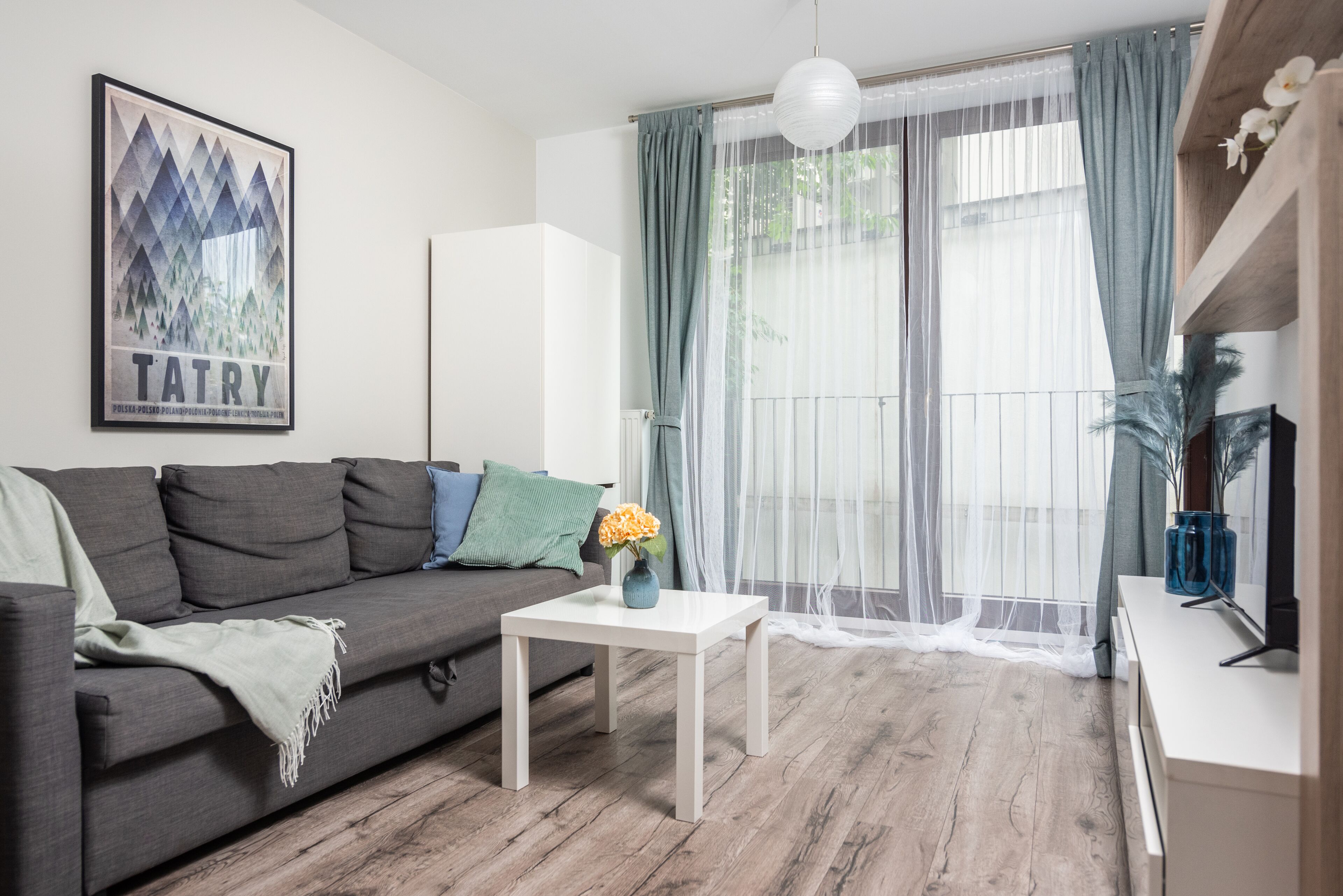Ein modernes Wohnzimmer mit einem grauen Sofa, einem weißen Couchtisch und einem gerahmten Bild an der Wand.