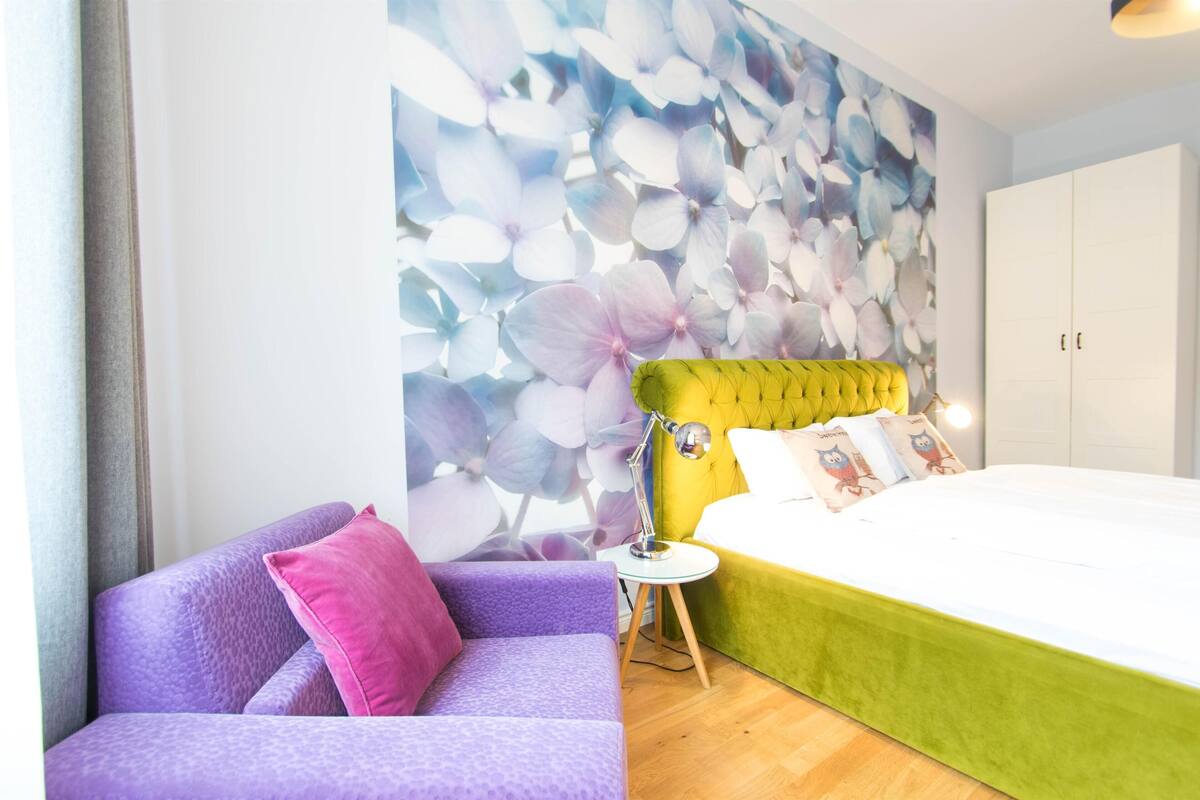 Une chambre à coucher comprenant un lit, un canapé, une table de chevet et un mur orné d ’une fresque florale.