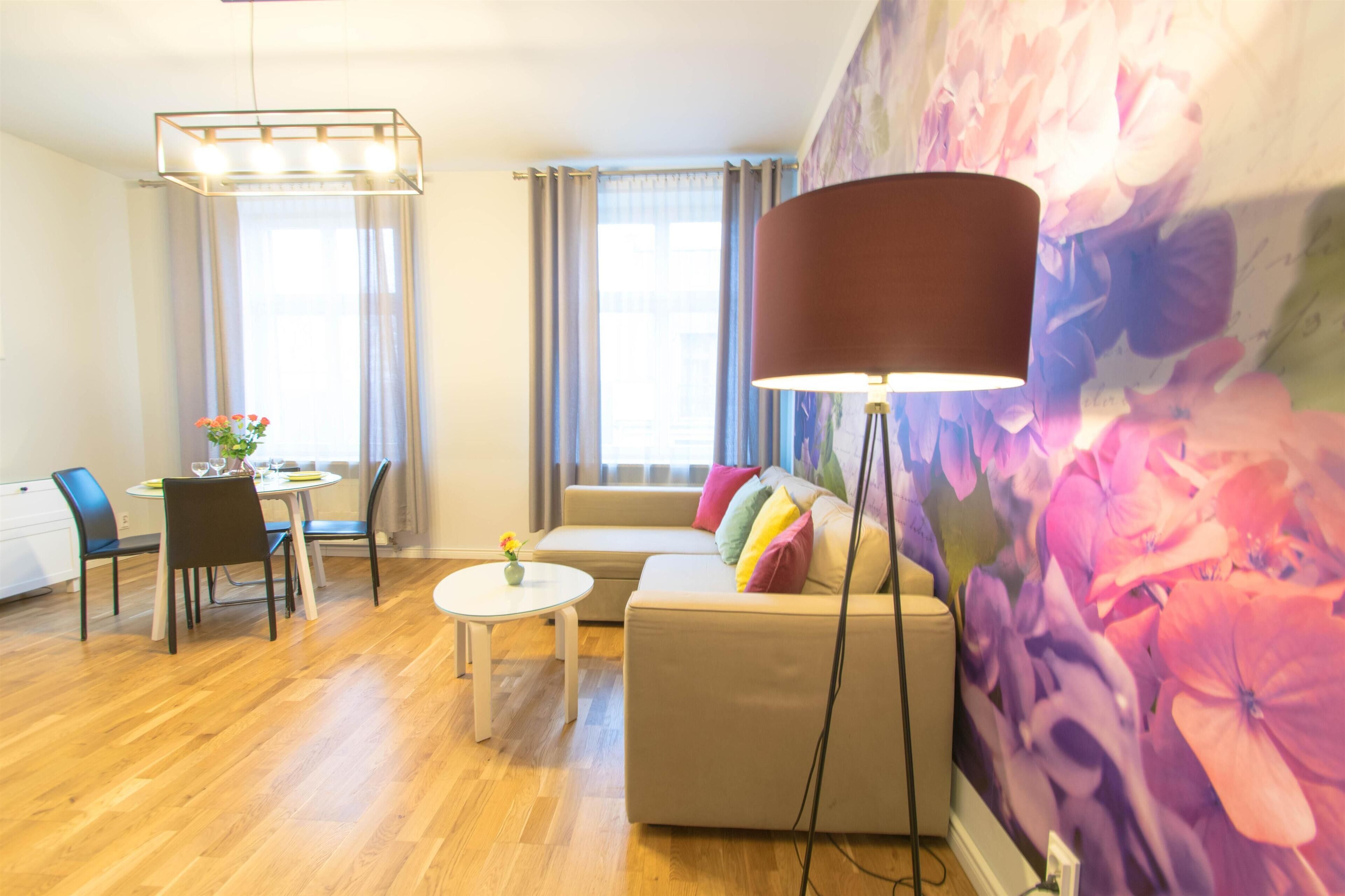 A modern living room with a sofa, a dining table with chairs, a round coffee table, and a floor lamp.