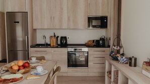 Een moderne keuken met een roestvrijstalen koelkast, oven en magnetron. Er staat een ontbijtje klaar op het aanrecht met eieren, toast en koffie.