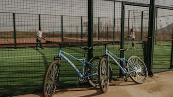 A blue bicycle leaning against a green fence in a fenced area.