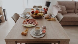 Een eettafel met diverse soorten eten, zoals fruit, gebak en een koffiekop.