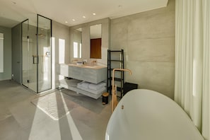 A modern bathroom with a glass shower enclosure, a large bathtub, and a vanity with a mirror.