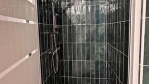 A small, enclosed shower stall with a handheld showerhead and a drain. - Le Nid Douillet - Studio (Beauvais)