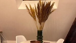 A dining area with a round table, two white chairs, a wooden bowl, and a vase with dried plants. - Le Nid Douillet - Studio (Beauvais)