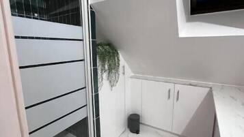 Een moderne keuken met witte kasten, een marmeren aanrechtblad en een ingebouwde televisie.