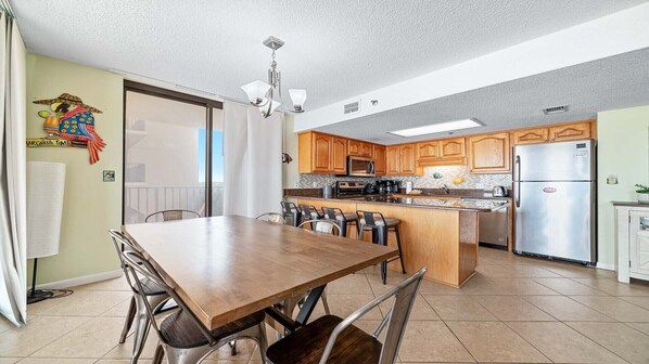 A modern kitchen with wooden cabinets, stainless steel appliances, and a central island with seating. - Beachfront! 3RD Floor Corner unit!! Great Winter Rates!! (Orange Beach)