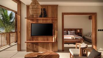 Una habitación amplia con un televisor grande montado en una pared de madera, un balcón con barandilla de madera y una cama con cabecera de madera.