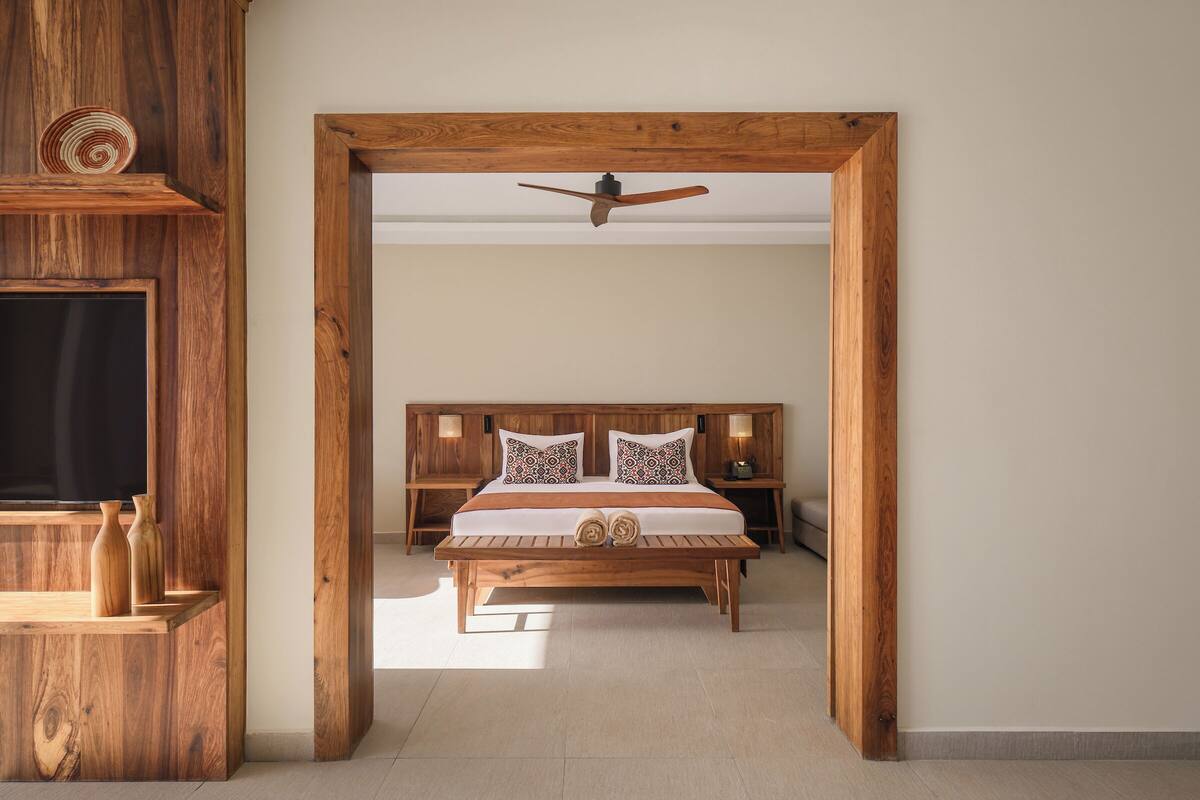 A wooden-framed bedroom with a bed, bedside tables, and a ceiling fan.