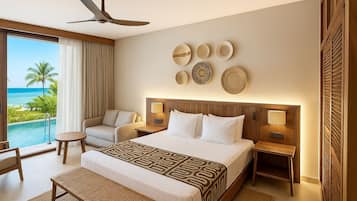 A hotel room with a large bed, two bedside tables, a ceiling fan, and a view of the ocean.