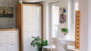 A modern living room with a wooden floor, a grey sofa, a white desk, and a large window. - RentPlanet - Świętego Mikołaja (Wroclaw)