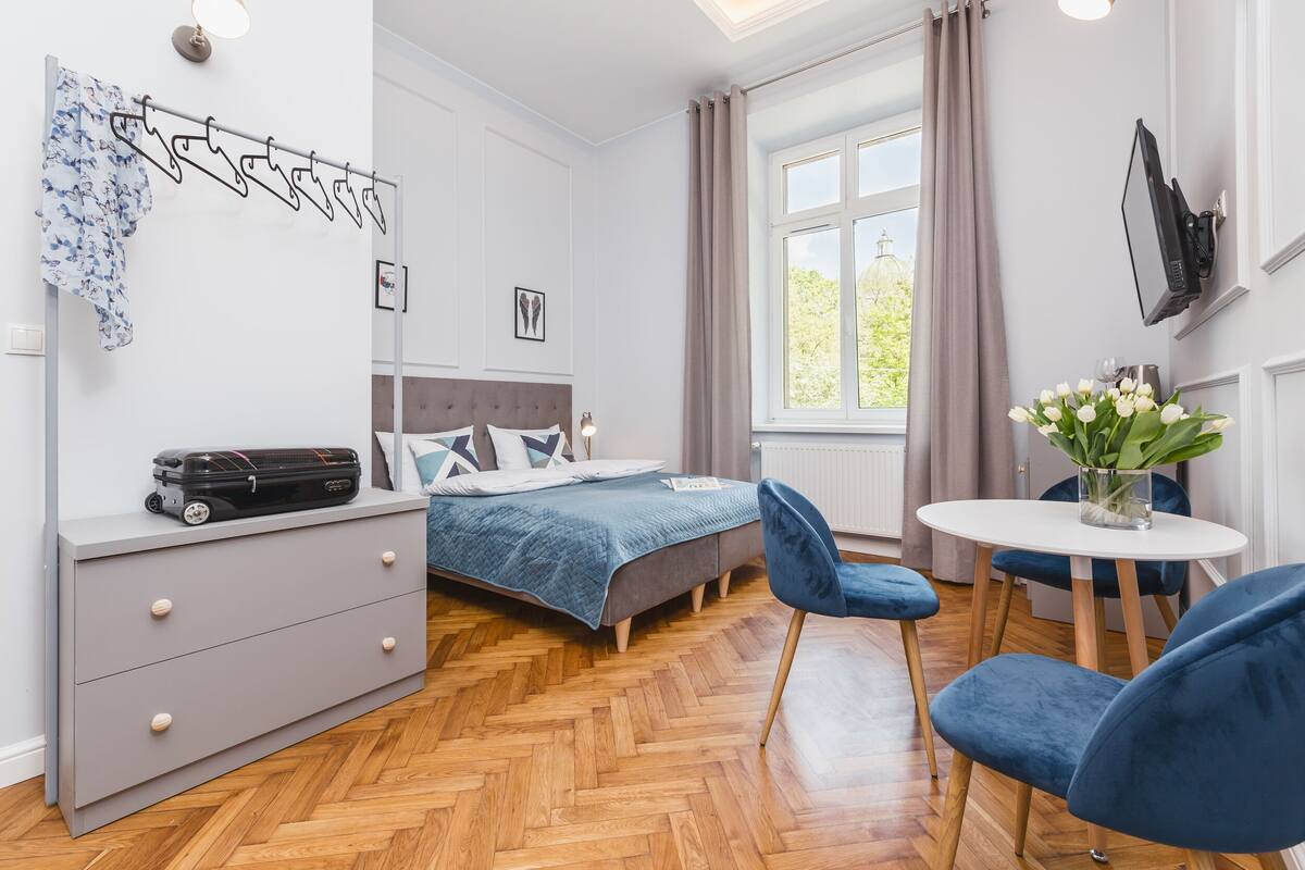 A modern bedroom with a bed, dresser, and a small dining area.