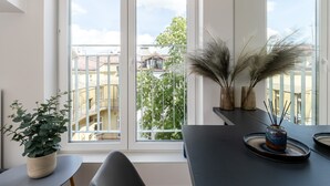 A modern apartment with large windows, a dining area with a table and chairs, and a potted plant. - Smart Apartments- Old Town Train Station (Kraków)