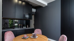 A modern kitchen with dark walls, a wooden dining table, and pink chairs. - Smart Apartments- Old Town Train Station (Kraków)