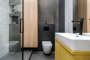A modern bathroom with a toilet, a sink, and a shower area. - Smart Apartments- Old Town Train Station (Kraków)