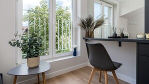 A modern kitchen with a large window, a dining table, and a chair. - Smart Apartments- Old Town Train Station (Kraków)