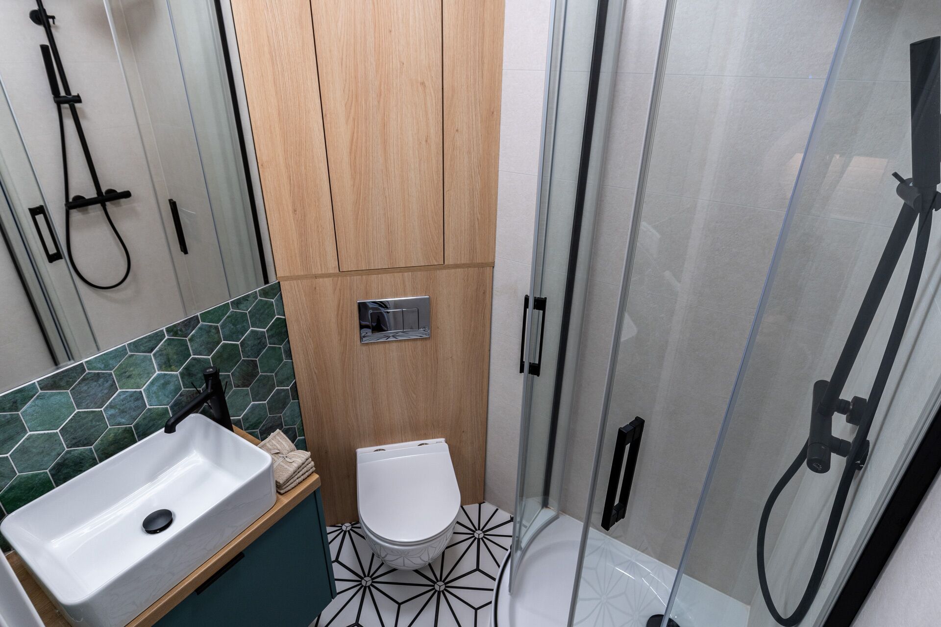 A compact bathroom with a sink, toilet, and shower.