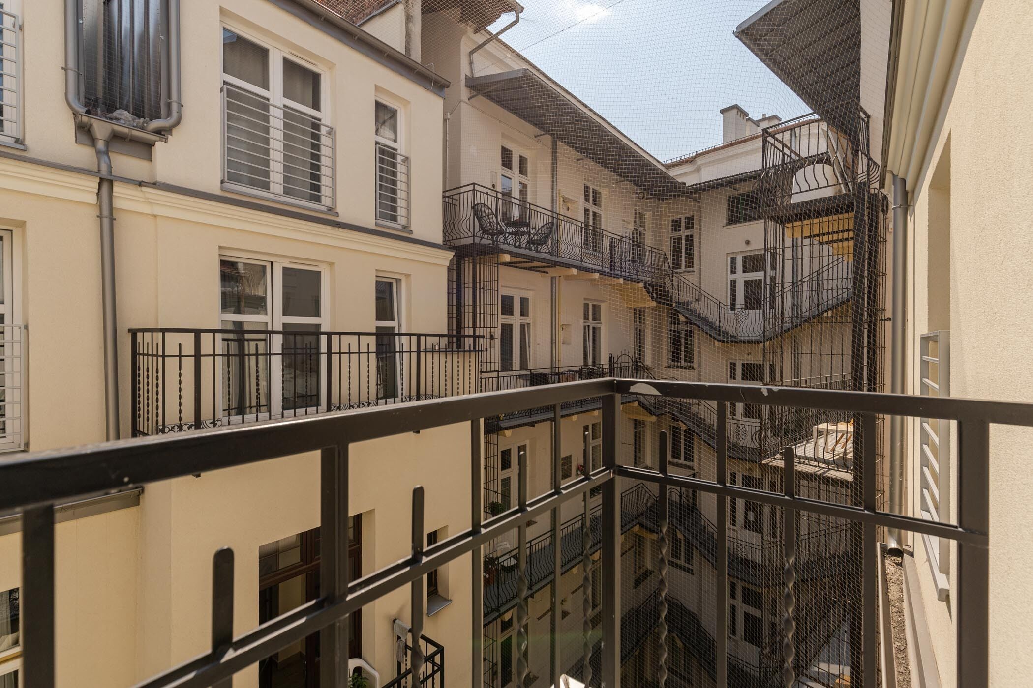 A multi-story building with balconies, staircases, and a view of adjacent buildings.