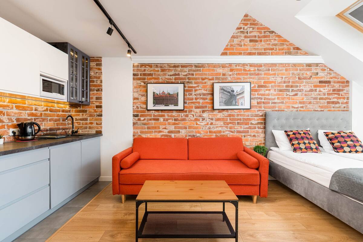 Un espacio habitable compacto con cocina, sofá, cama y mesa.