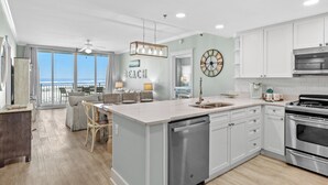A modern kitchen with white cabinets, a stainless steel dishwasher, and a large island with a sink. - Waterscape B201 ~ Oceanfront 3BR ~ Amazing Gulf Views! (Fort Walton Beach)